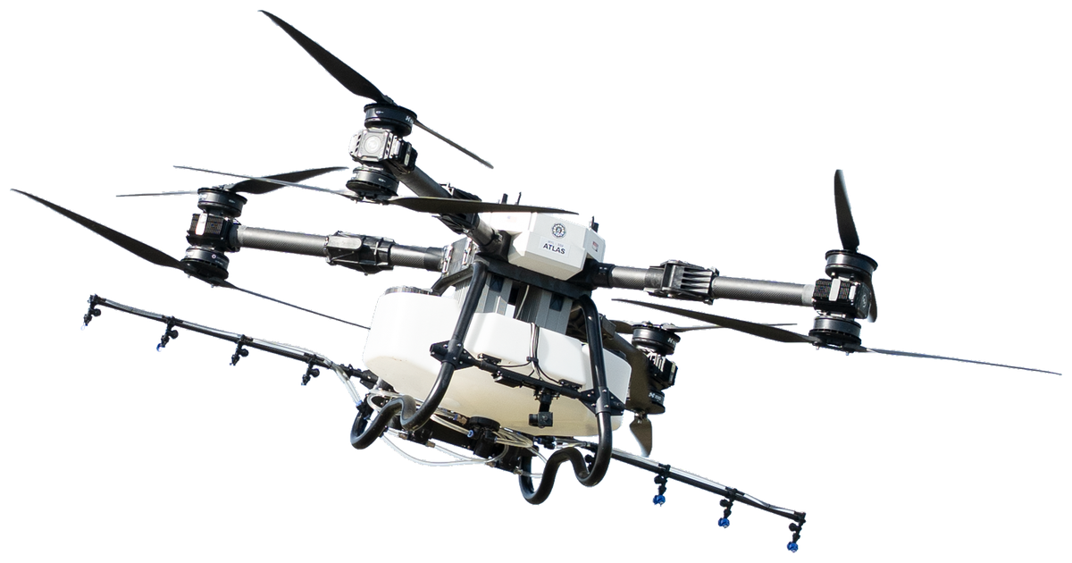 Hylio ATLAS spray drone in flight, three-quarter view, spray booms and nozzles under the tank